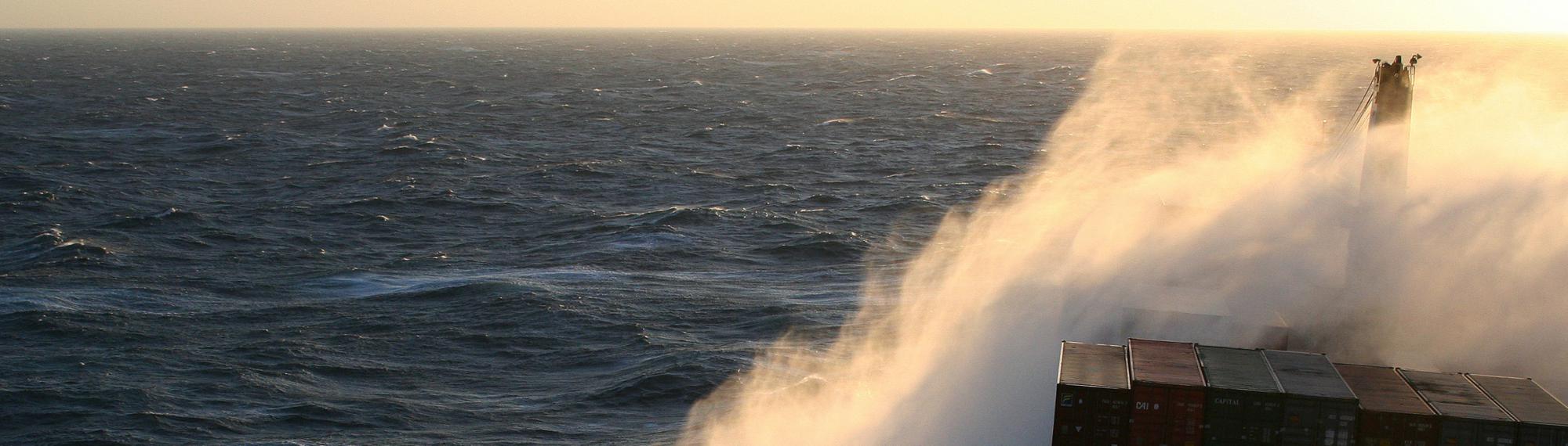 Containerschiff bei Seegang - Wellen brechen an Bug